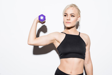 Portrait of young beautiful woman making physical exercises with dumbbells isolated on white...