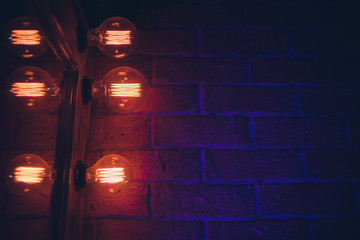 Decorative antique edison style light tungsten bulbs against brick wall background.