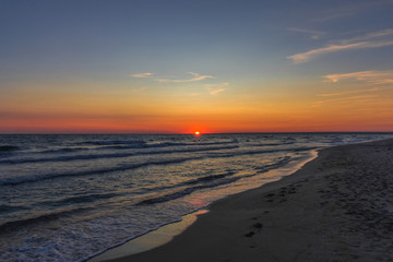 The sun sets over the horizon on the sea