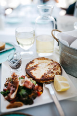 Traditional grilled cheese with salad and slice of lemon on white plate
