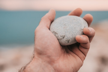 Smooth stone closeup in hand on the background of the sea, sea pebbles