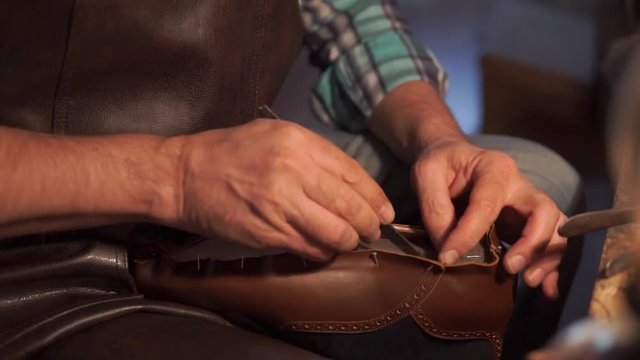 ancient workshop with expert shoemaker during the processing of leather to produce shoes with vintage effect