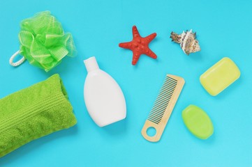Flat lay photo organic bath products. Spa cosmetics. Green cotton towel, sponge, shampoo bottle, wooden hair brush, soap bar and seashells. Natural cosmetics set