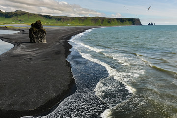 Rocks formation on Dyrholaey cape with black sand beach near  Vik town, Iceland in summer on sunny day
