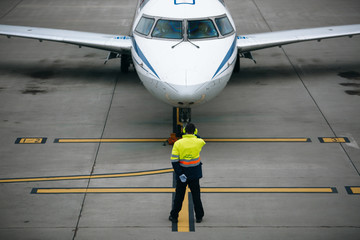 Back view of airport flight coordinator meeting passenger aircraft