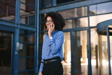 Businesswoman walking out of the office building talking on phon