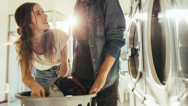 Couple Doing Laundry Together Picking Clothes From A Basket