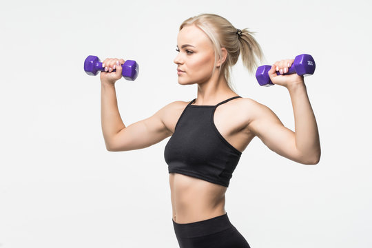 Side view portrait of a pretty young sportswoman doing exercises with dumbbells isolated on a gray background