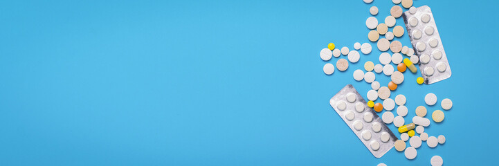 Pills of different colors on a blue background. Concept of the pharmaceutical industry, medicine,...