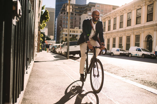 Smiling businessman going to work on bike