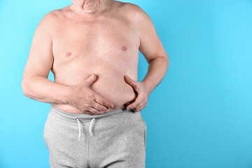 Naklejka premium Fat senior man on color background, space for text. Weight loss