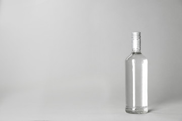Bottle of alcoholic drink on grey background. Space for text