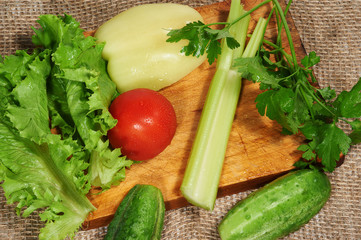 Salad, tomatoes, peper, cucumbers, smallage and parsley on cutting board