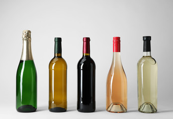 Bottles with different types of wine on light background