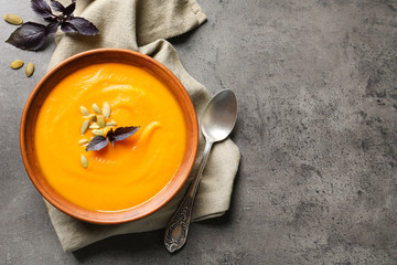 Flat lay composition with bowl of pumpkin soup and space for text on gray background