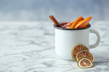 Mug with red mulled wine on marble table. Space for text