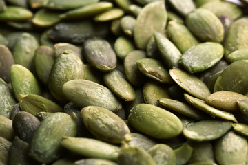 Shelled raw pumpkin seeds as background, closeup