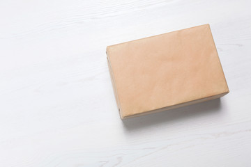 Parcel box wrapped in kraft paper on wooden background with space for text