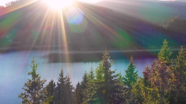 Autumn color forest, aerial view over colorful autumn trees, towards lake. Mountain lake and forest in autumn season. Beautiful sun light. Mountain lake with turquoise water in fall season. October. 