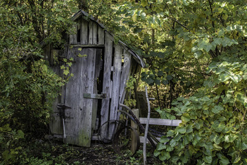 Old Wooden Corn Crib Shed. Abandoned old wooden shed with antique farm tools being overtaken by the...