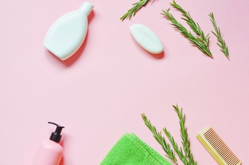 Flat lay beauty border. Shampoo, liquid soap, green terry towel, rosemary herbs and wooden comb. Organic bath products