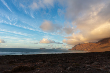 mountain with a cap of clouds on the ocean at sunset