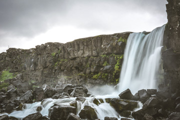 Fototapeta premium Oxararfoss waterfall in Pingvellir or Thingvellir National Park in summer in Iceland - water motion blur, vintage colors