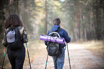 Nordic walking. Portrait of child and curly woman in an autumn. Child and woman having fun in the...
