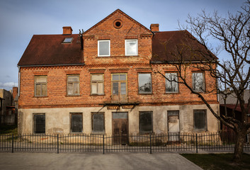 Abandoned old brick building in city center of Kandava, Latvia. Some of the windows are missing and covered by cardboard. Shot in April 2015.