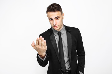 An excited business man in a black suit convinces the viewer of something. Handsome guy gesturing. on white background.
