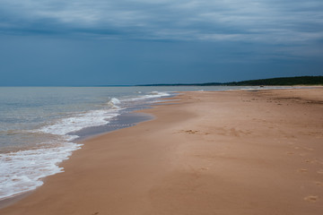 White sand beach with waves and blue sky on cold summer day in Latvia, Pavilosta
