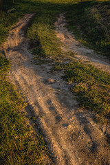 Bad shaped country road in perspective in summer with visibable car tire trails
