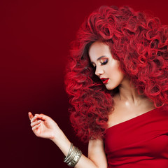 Portrait of beautiful young woman with red hair on red background