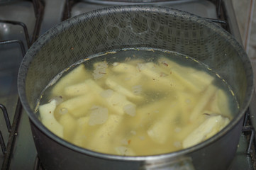 for french fries, sweet yellow potatoes cut into toothpicks, inside pan with water being cooked