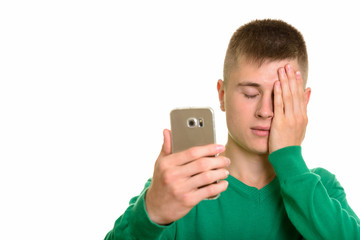 Young Caucasian man holding mobile phone looking tired with eyes