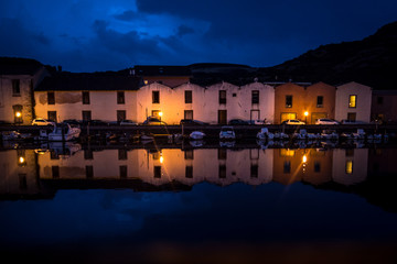 Night city view of Bosa harbor, Sardinia, Italy. Colorful houses, boats and dark blue sky...