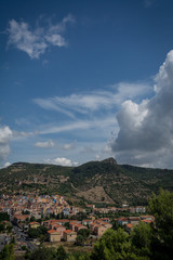 Fototapeta na wymiar City view of Bosa, Sardinia, Italy from above. Colorful houses, mountains and cumulus clouds on a sunny day.