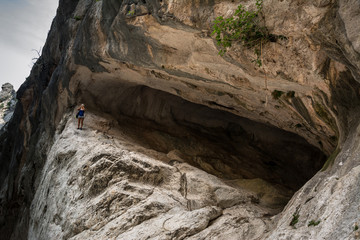 Young woman standing in the background of canyon and taking photo of canyon.  Shot in Gola Su Gorropu canyon, Sardinia, Italy - important natural site in Sardinia.