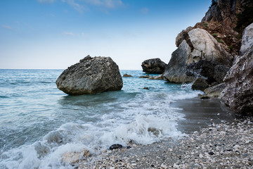 Cala Gonone empty beach in Sardinia with rocks and waves on an overcast summer day, perfect vacation place. Seascape view.