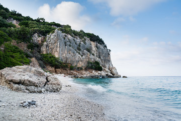Cala Gonone beach in Sardinia with rocks  on an overcast summer day, perfect vacation place. Seascape view.