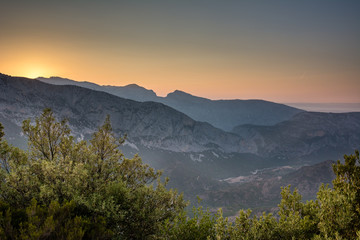 Obraz premium Panoramic Mountain Landscape view during a beautiful sunset, with layered blue mountains, Sardinia, Orosei region.