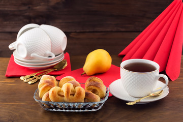 Delicious Breakfast of pastries with fruit filling, ripe pear and tea in a white mug.