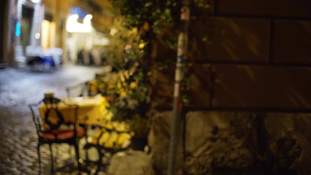 Blurred background of dark street corner with table and chairs of outdoor cafe
