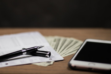 using smartphone, account book bank and pen and money for finance and banking concept. Focus pen
