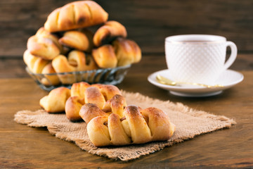 Confectionery baked with fruit filling, porcelain tea pair, wooden background.