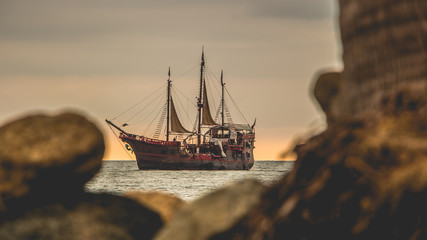 Gran barco pirata navegando por la costa durante el atardecer.