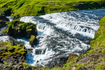 Countryside with trail near famous Skogafoss Waterfall, Iceland on sunny summer day and blue sky