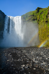 Famous Skogafoss waterfall located in Iceland with double rainbow on a sunny day. Nobody in the scene.