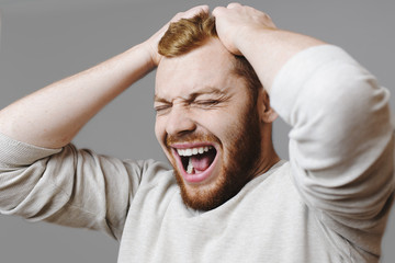 Stressed man tearing hair and screaming