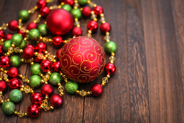 Mix of red, green, and golden Christmas balls. New Year decor for tree on dark wooden background